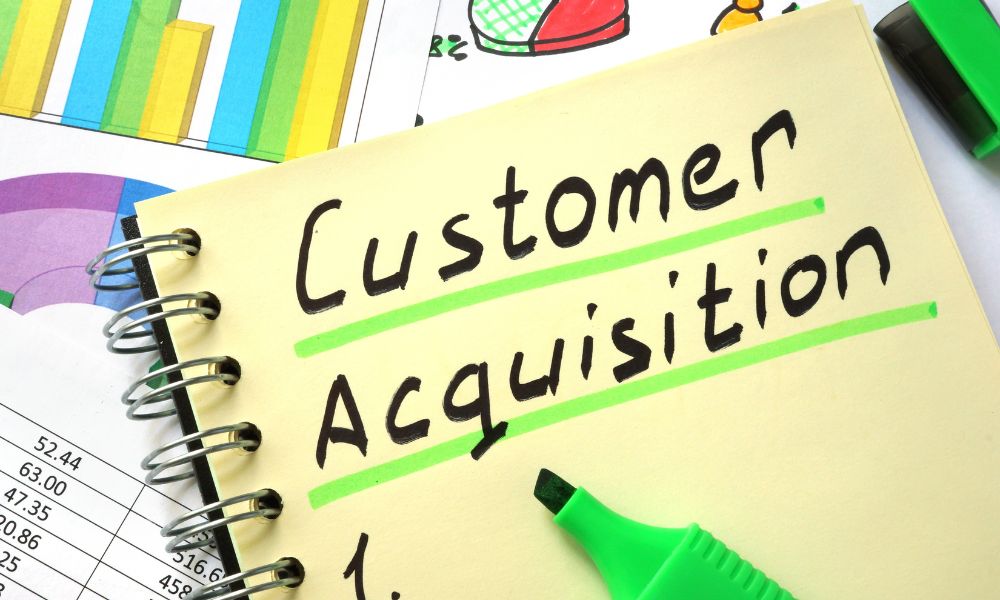 Customer acquisition written on a notebook with charts in the background.
