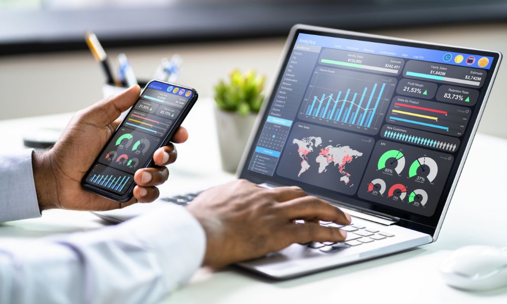 Man looking at omnichannel analytics data on cell phone and laptop.