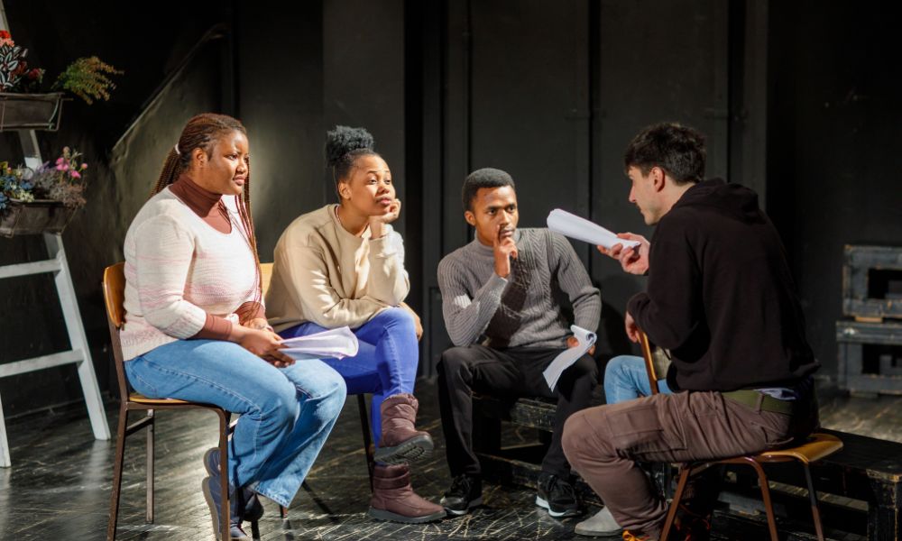 Drama students receiving acting tips from an experienced actor.