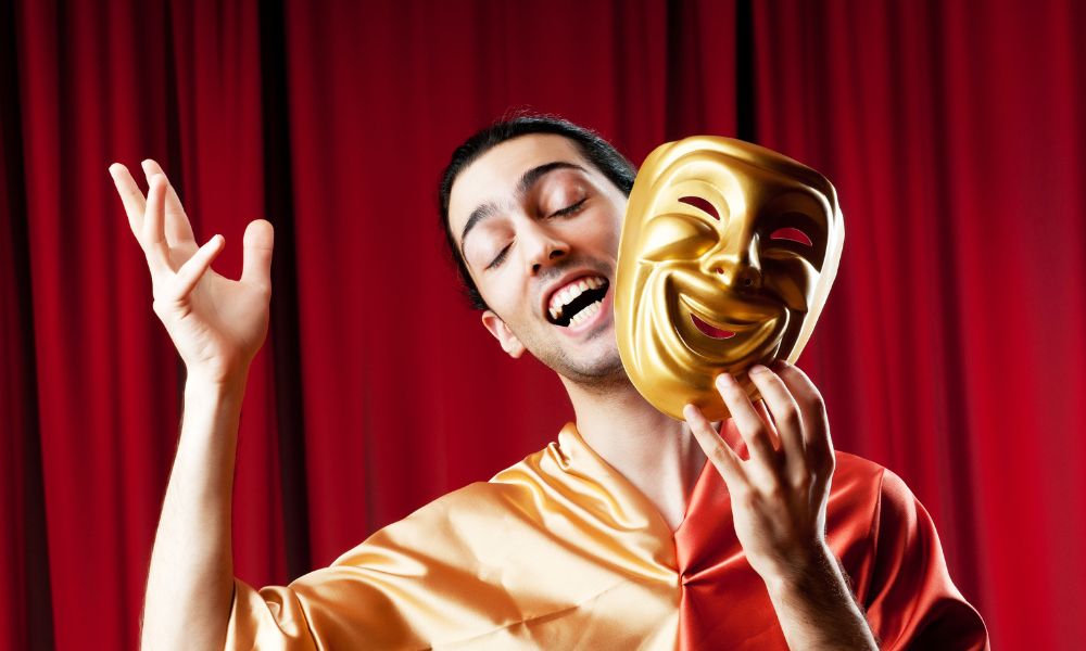 Stage actor holding a mask and doing a monologue.