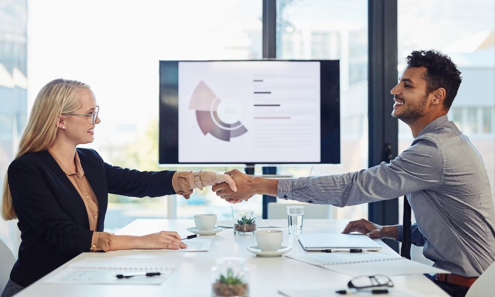 A man and a woman shaking hands after closing a B2B sale.