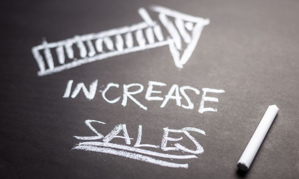 An arrow with the words ‘increase sales’ written with chalk on a chalkboard.