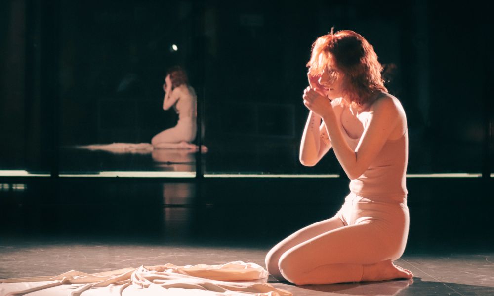 Actor on stage with a mirror in the background.