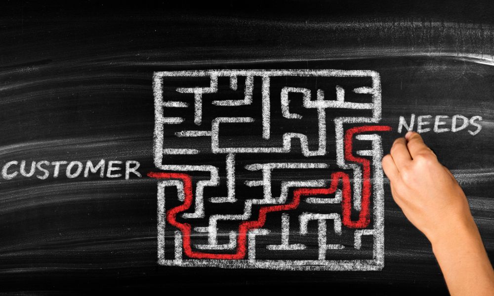 Maze drawn with chalk on a chalkboard with the word customer written on one side of the maze and the word needs on the other side.
